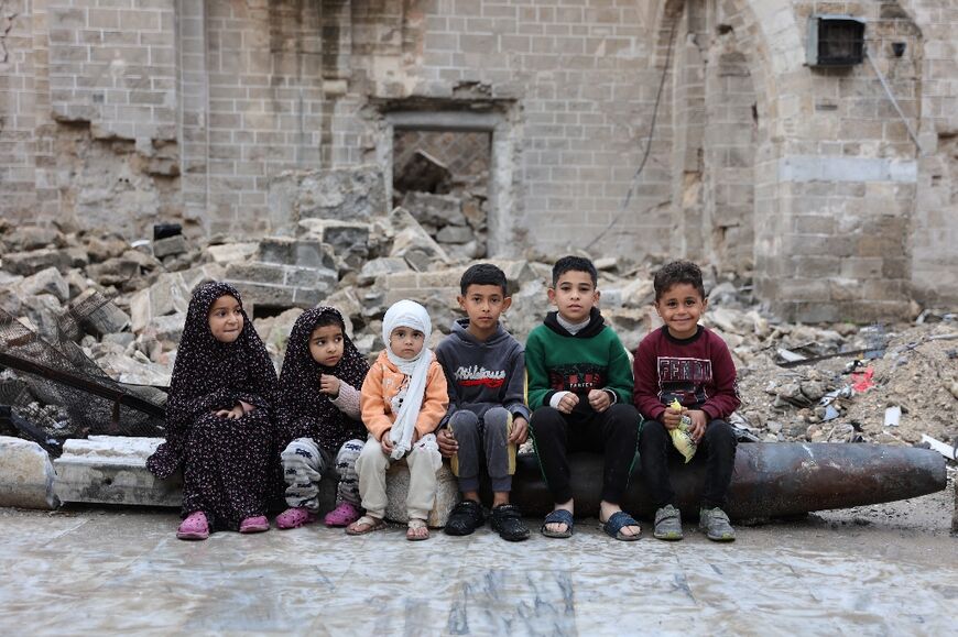 Palestinian children pose  in the courtyard of Gaza City's historic Omari Mosque, heavily damaged in Israeli bombardments, after the morning prayer on the first day of Eid al-Fitr 