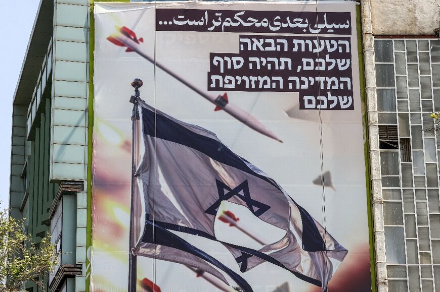 A banner in Tehran shows missiles and drones flying past a torn Israeli flag, with text in Persian reading "the next slap will be harder" and in Hebrew "your next mistake will be the end of your fake state"
