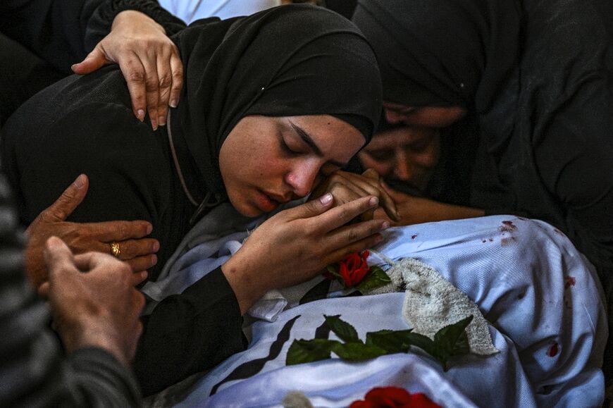 A funeral procession for 13 Palestinians killed in the Israeli army raid passed through roads piled with rubble