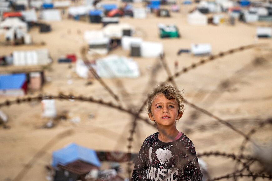 A child stands behind barbed-wire near a camp housing displaced Palestinians in Rafah