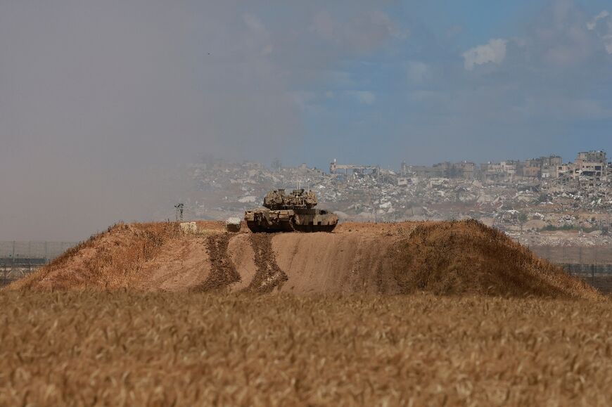 An Israeli army tank takes a position in southern Israel near the border with the Gaza Strip as smoke billows in the background from bombardment