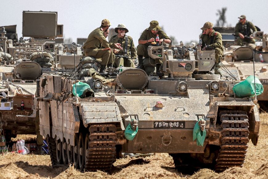 Israeli soldiers sit atop an infantry fighting vehicle near the border with the Gaza Strip on April 30, 2024