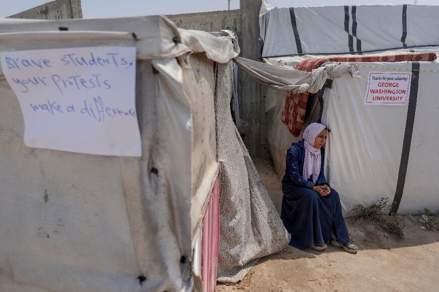 A displaced Palestinian woman in central Gaza sits outside a tent with signs thanking pro-Palestinian student solidarity initiatives on US and Canadian campuses