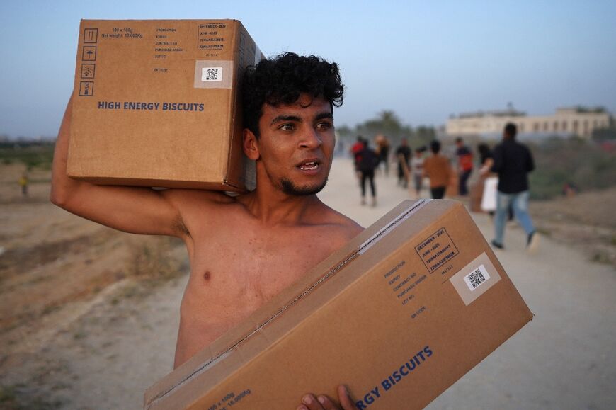 A man carries boxes of food after Palestinians rushed trucks transporting aid from the pier