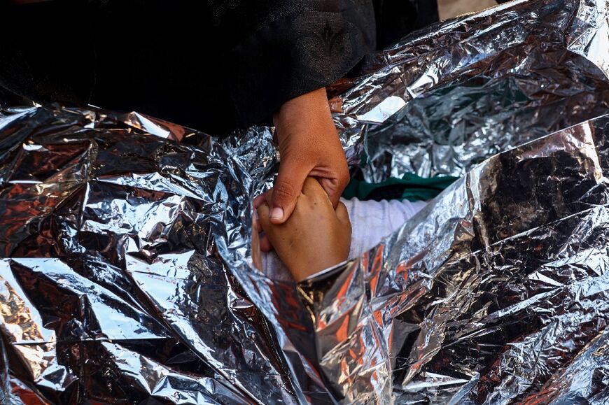 A woman holds the hand of a boy killed in the Israeli strike