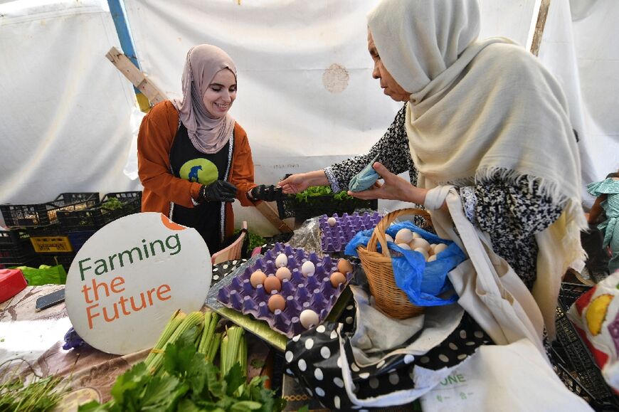 Ibtissem Mahtout (L) speaks with a customer at the Friday market
