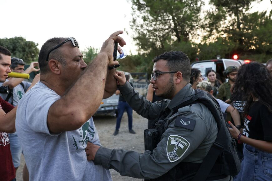 An Israeli border policeman pushes an activist as protesters confront settlers near Beit Jala