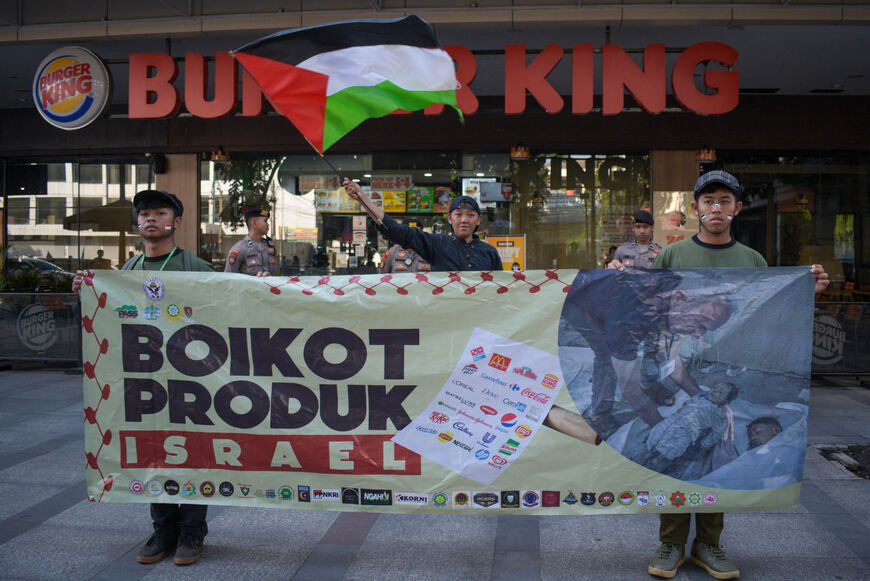 I sostenitori pro-palestinesi tengono uno striscione di boicottaggio contro i prodotti che ritengono possano sostenere Israele, a Bandung, Giava Occidentale, il 13 luglio 2024. (Foto di TIMUR MATAHARI / AFP) (Foto di TIMUR MATAHARI/AFP tramite Getty Images)
