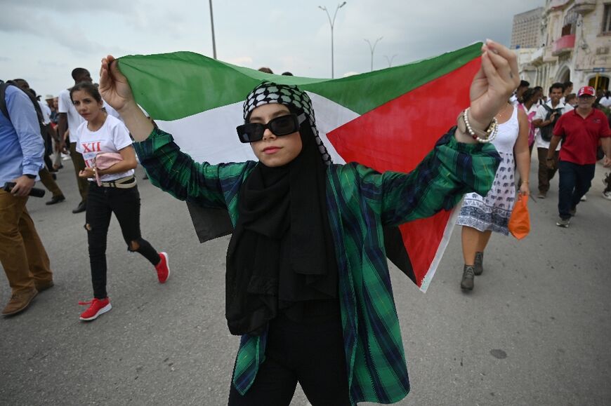 A woman holds a Palestinian flag as people march along Havana's waterfront during a pro-Palestinian rally