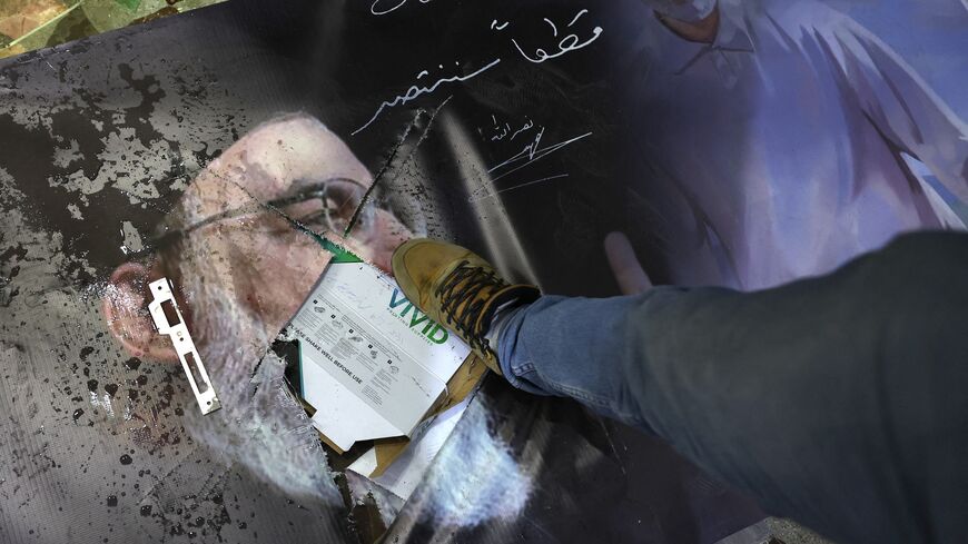 Un uomo calpesta un ritratto danneggiato del leader di Hezbollah assassinato Hassan Nasrallah e del defunto generale iraniano Qassem Soleimani mentre i siriani saccheggiano l'ambasciata iraniana nella capitale Damasco, l'8 dicembre 2024.
