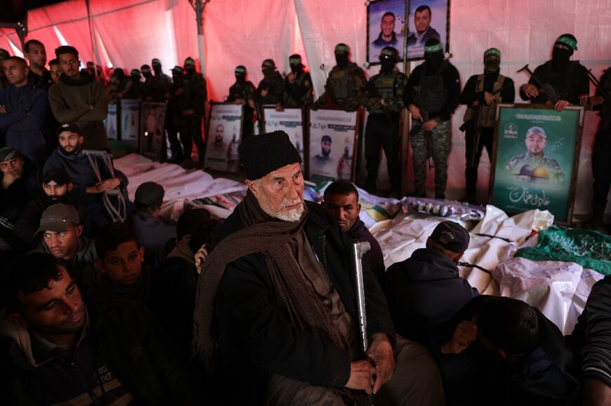 An elderly man, along with Palestinian civilians and Hamas fighters, attends a funeral ceremony near Gaza City for 40 militants and civilians killed during the war with Israel