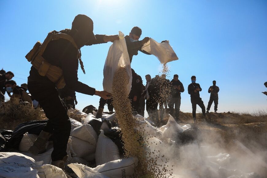 Members of the new Syrian security forces empty sacks of captagon into a ditch to burn them near Damascus