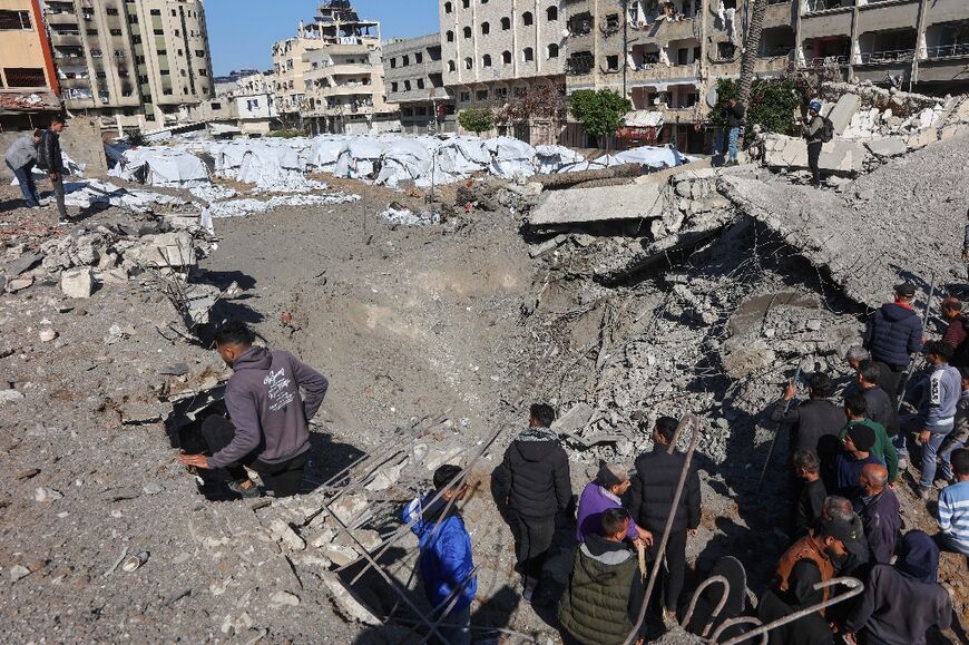 Palestinians inspect a crater at the site of Israeli strikes on a makeshift displacement camp in Gaza City