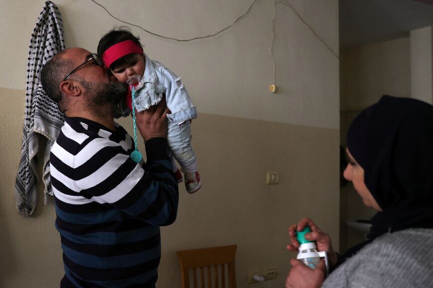 Rami al-Arouqi holds five-month-old Jannah, who the SOS Children's Villages NGO had previously taken care of