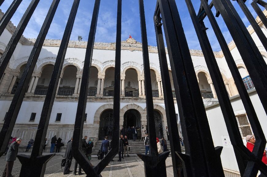 People stand in the yard of the Tunis Palace of Justice as the first hearing against detainees accused of involvement in a conspiracy case against state security starts