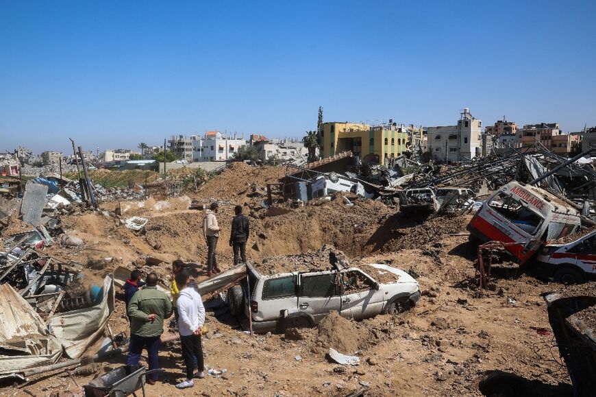 Palestinians inspect the damage at an ambulance repair yard hit in Israeli strikes in the al-Maghazi refugee camp in the central Gaza Strip 