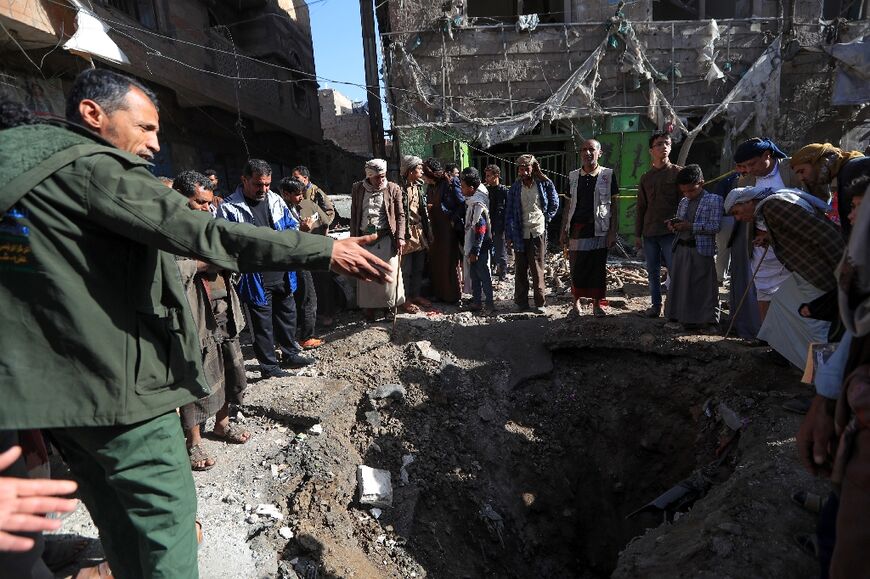 People assess the damage caused by a US air strike in Sanaa