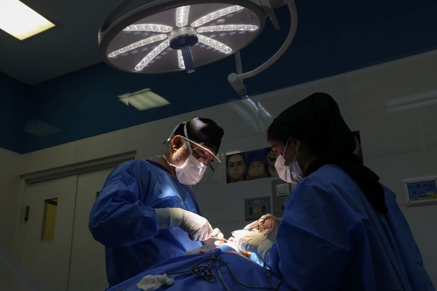 Iranian surgeon Hamidreza Hosnani performs a nose operation at his private clinic in Tehran on March 4, 2025