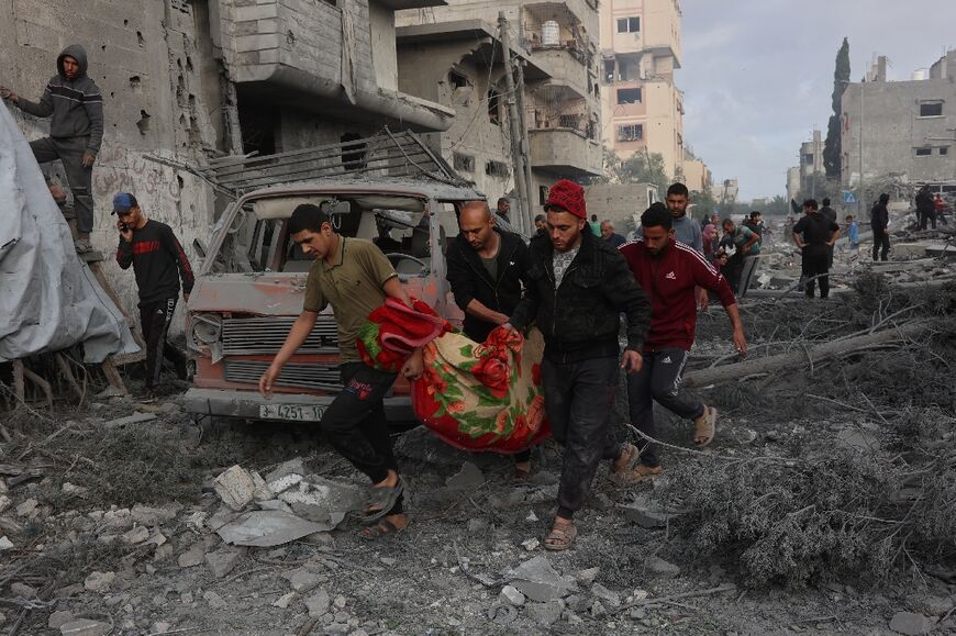 Palestinians carry a victim's body after it was dug out from the rubble of a bombarded school in Gaza City