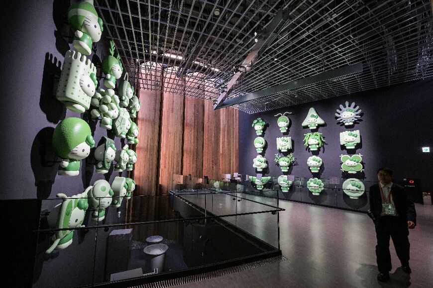 A visitor walks past a Hello Kitty display with different types of algae, at the Japan pavilion