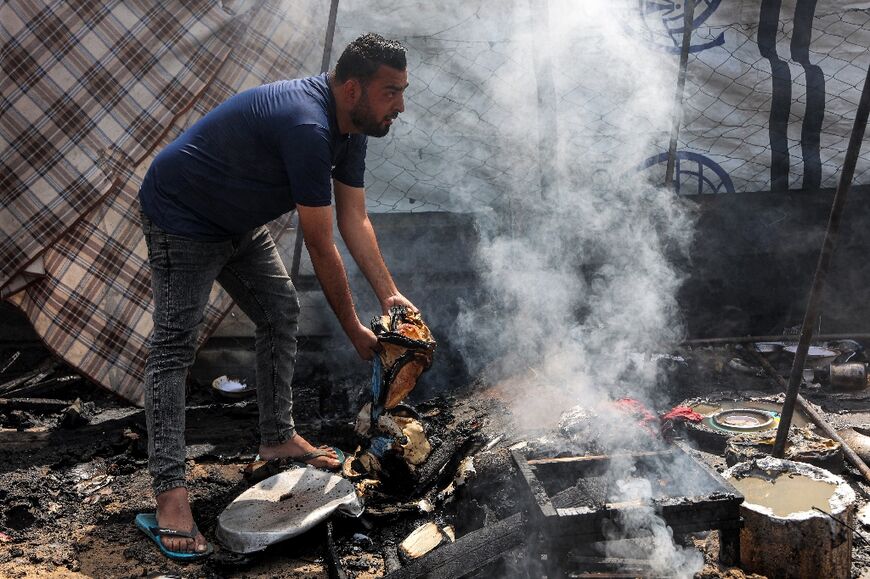 A man holds burnt bread by a tent encampment for Palestinians displaced by the war
