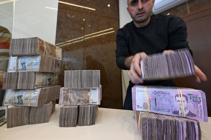 An employee stacks Syrian bills at a Damascus currency exchange -- a trade outlawed under former president Bashar al-Assad