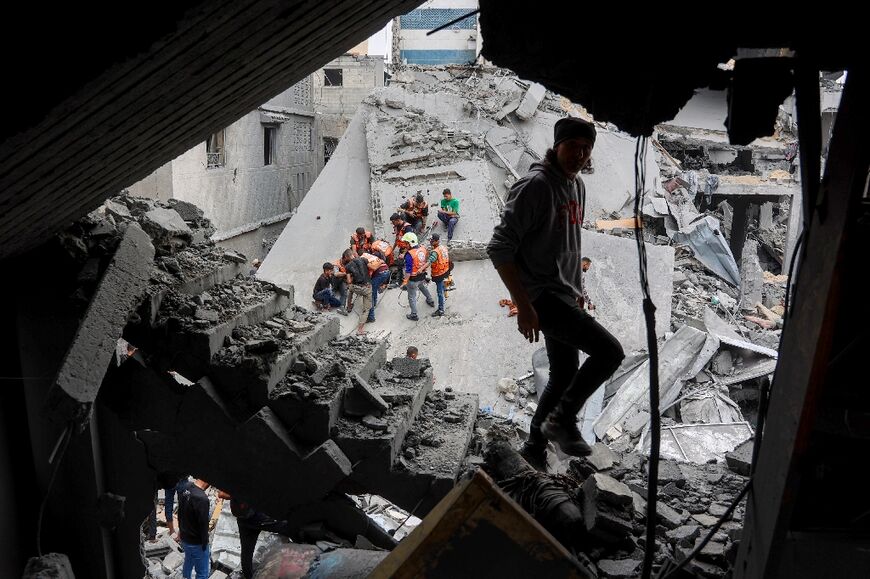A man walks amids the rubble of a building as Palestinian rescuers work at the site of an Israeli strike on a residential area in Gaza City's Shujaiyya neighbourhood
