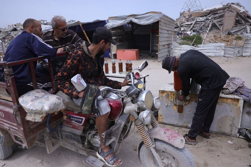 A Palestinian man sells fuel, extracted from recycled plastic at a makeshift plant, at a roadside kiosk in the northern Gaza Strip
