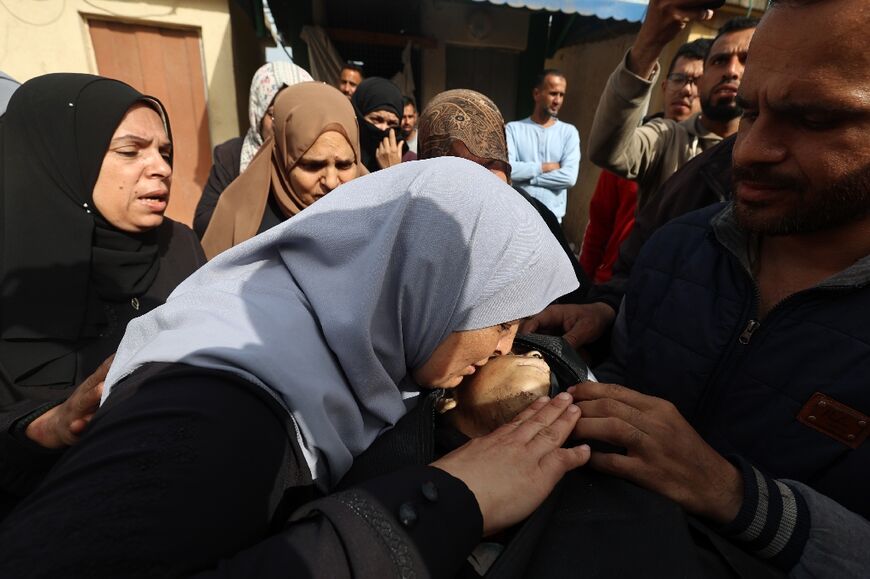 A mourner kisses the face of Palestinian child Ahmad Abu Saleh outside the Al-Aqsa Martyrs Hospital in Deir al-Balah