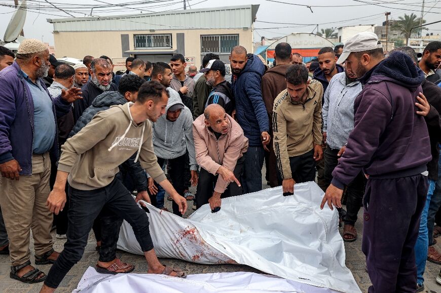 Men carry the bagged-body of one of the victims killed by Israeli air strikes on the Sabah family building in Deir el-Balah
