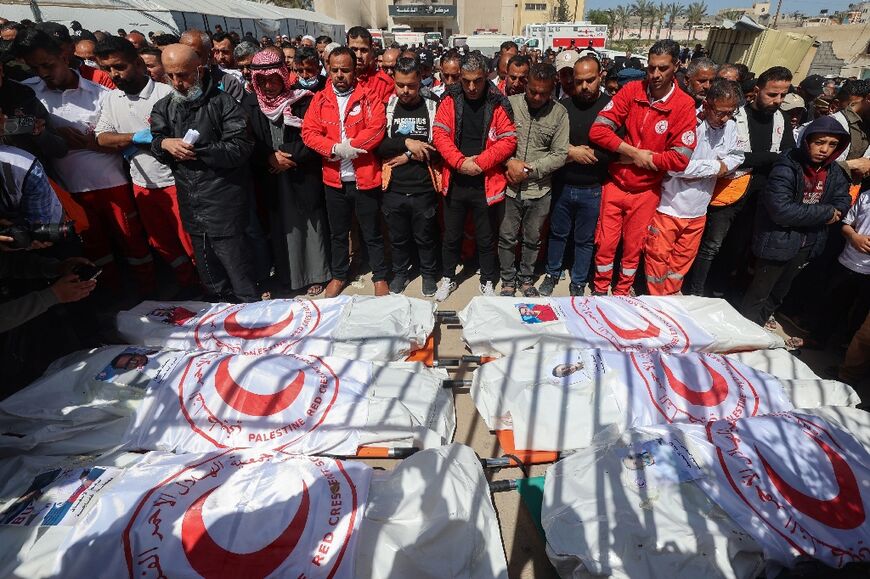 Members of the Palestine Red Crescent and other emergency services pray by the bodies of fellow rescuers killed a week earlier by Israeli forces
