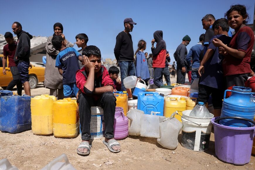 Palestinians attempt to collect water at a camp for displaced people in Gaza City