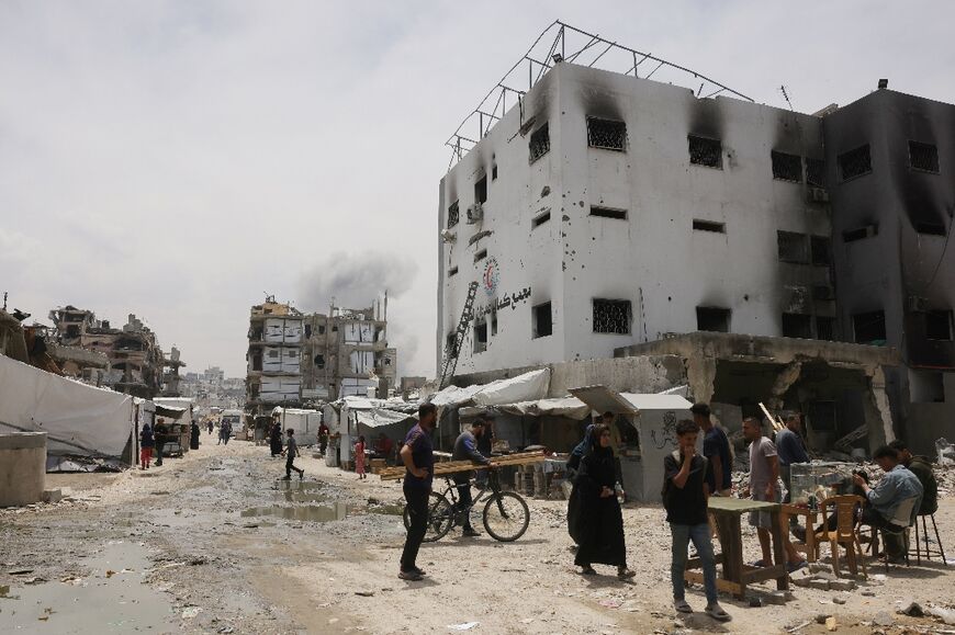 Palestinians near the damaged Kamal Adwan medical facility in northern Gaza as smoke from Israeli bombardment billows in the background