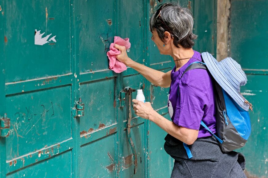 A left-wing activist cleans graffiti from the shutter of a Palestinian-owned shop in Old Jerusalem