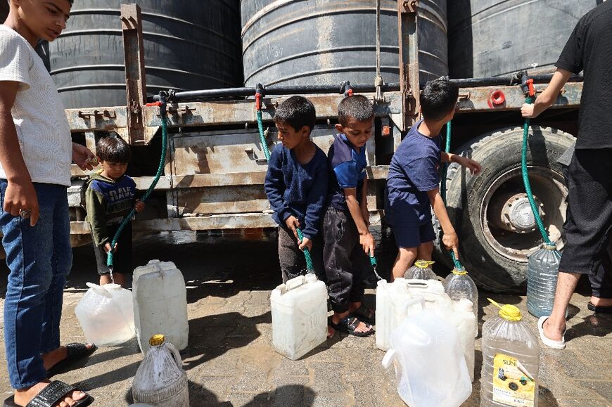 Palestinian boys fill their containers with water at a distribution centre in Nuseirat.
