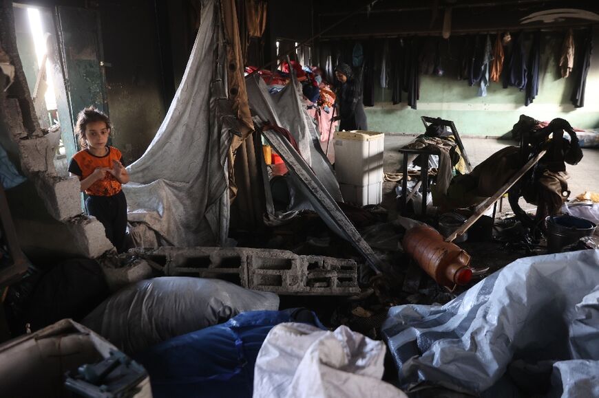 Palestinians look through the debris in a classroom after a strike hit a school serving as a shelter for displaced people