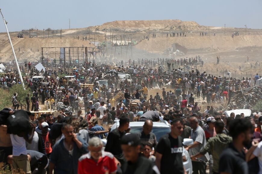 Displaced Palestinians carrying relief supplies return from an aid distribution centre in the central Gaza Strip on May 29, 2025