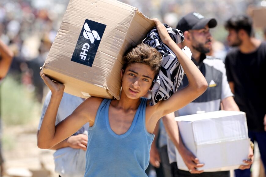 A boy carries a box of supplies from the Gaza Humanitarian Foundation, a private US-backed aid group that has bypassed the longstanding UN-led system