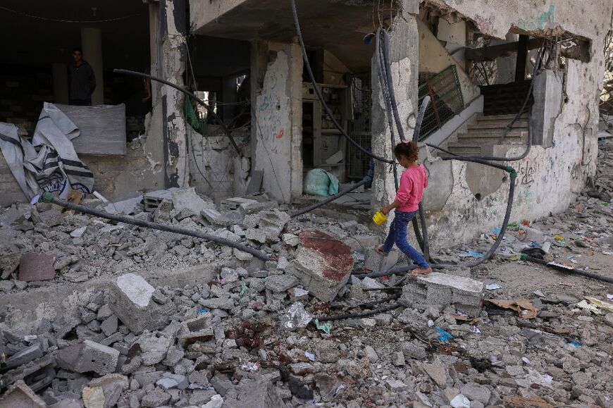 A Palestinian girl walks over the blood-stained rubble of a building hit in an Israeli strike in Jabalia