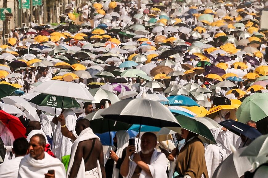 Muslim pilgrims use umbrellas to shade themselves from the sun