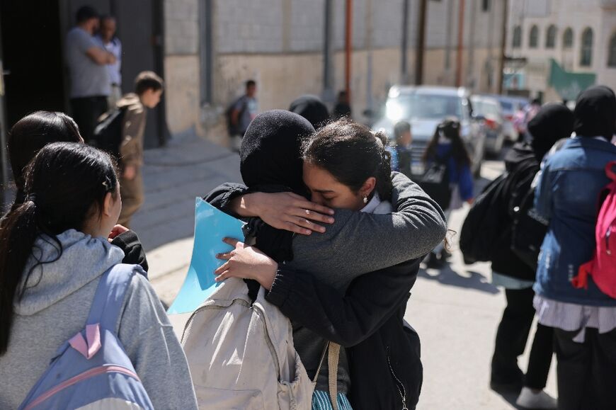 Palestinian schoolgirls embrace as they leave a UNWRA school