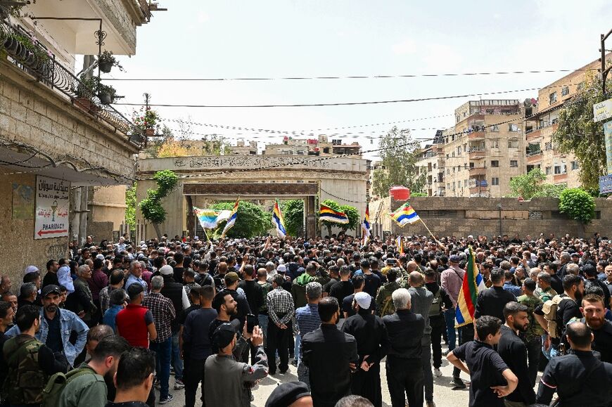 Syrian Druze wave flags and chant slogans during the funeral of seven people killed during clashes in April