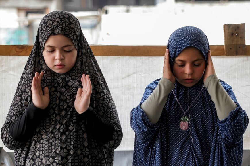 Two girls pray together during the second consecutive Eid al-Adha in Gaza under the shadow of war