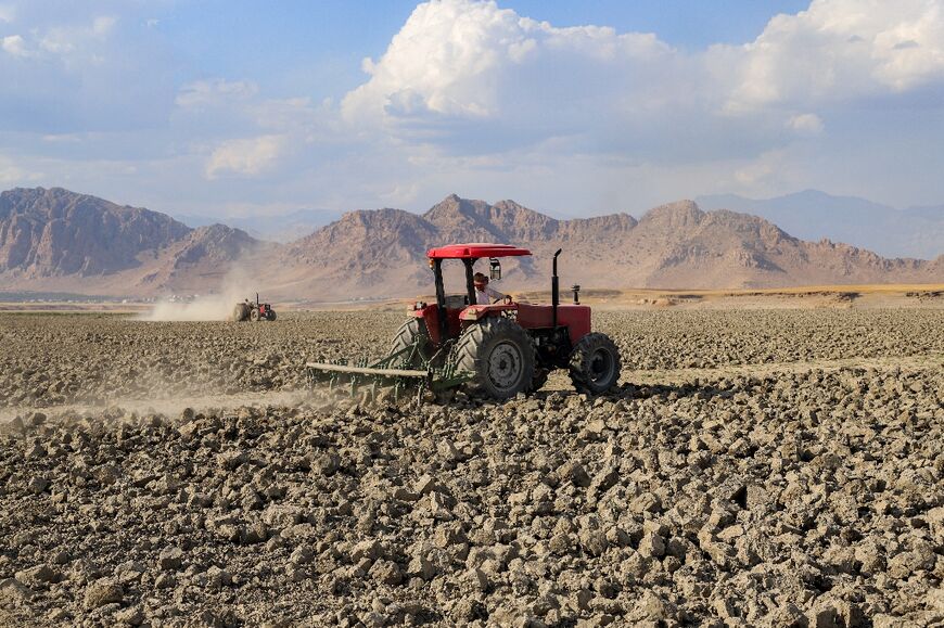 A farmer ploughs a field with a tractor near the village of Sarsian, at the edge of the Dukan dam reservoir