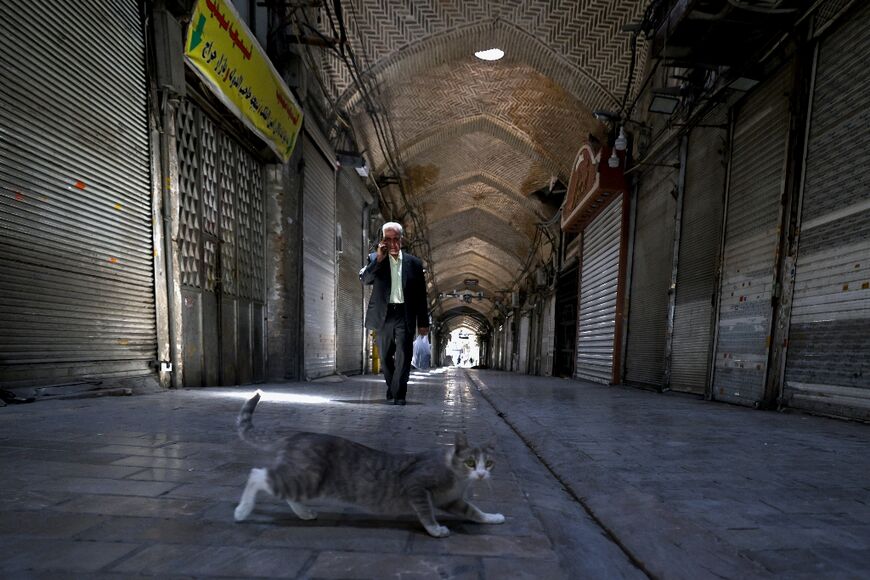 People walk past closed shops in Tehran's Grand Bazaar