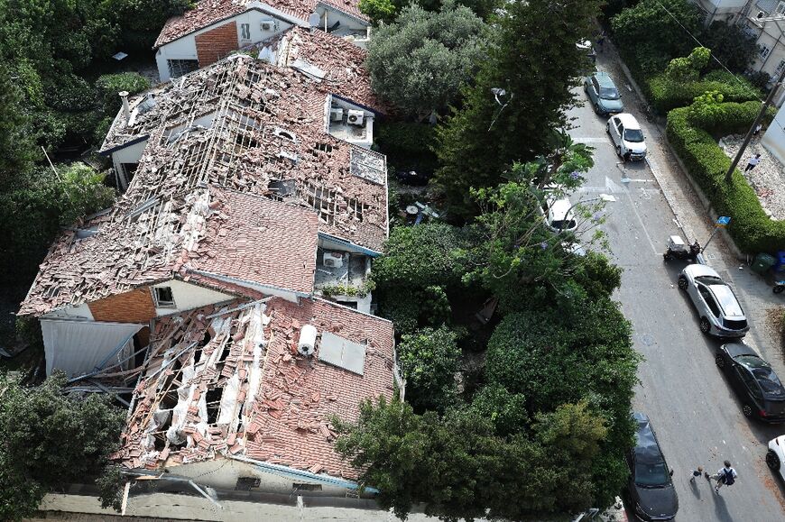 A father and child walk past destroyed houses at the site of an Iranian strike that hit a residential neighbourhood in the Ramat Aviv area in Tel Aviv