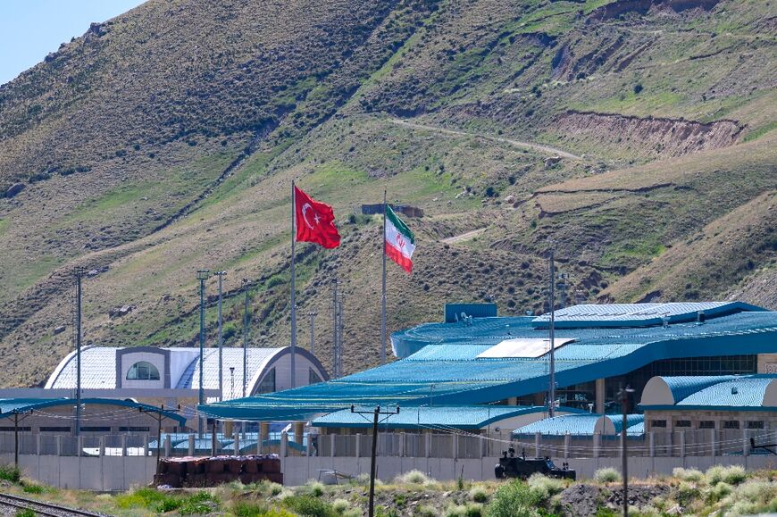 Iranian and Turkish flags fly over the Kapikoy crossing where officials say arrivals have remained steady despite the increasing violence in the air war between Israel and Iran
