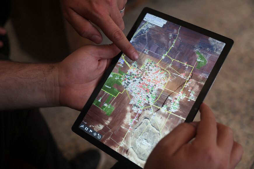 Syrian architect Abdel Aziz al-Mohammed (L) shows on a tablet an interactive map that he created, revealing the detailed conditions of each house in his village Tal Mardikh