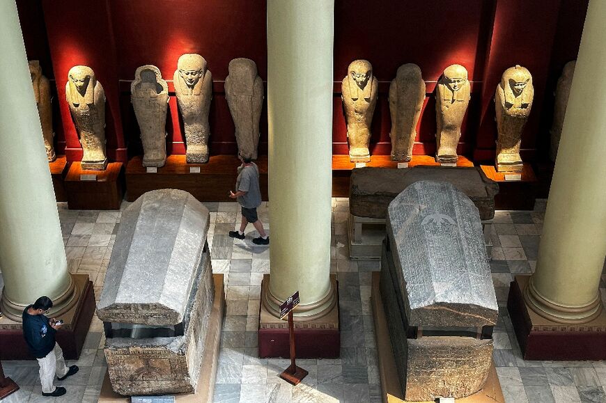 A man stands by ancient stone sarcophaguses displayed at the Egyptian Museum