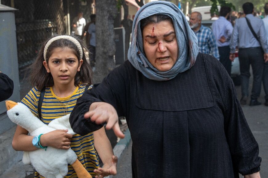A bloodied Iranian woman reacts after a reported Israeli strike on Keshavarz Boulevard in downtown Tehran